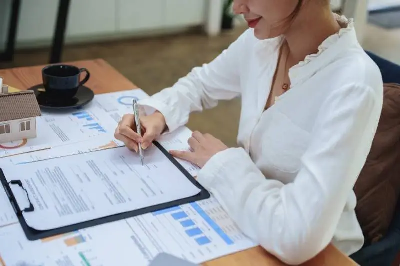 woman signing contract on desk