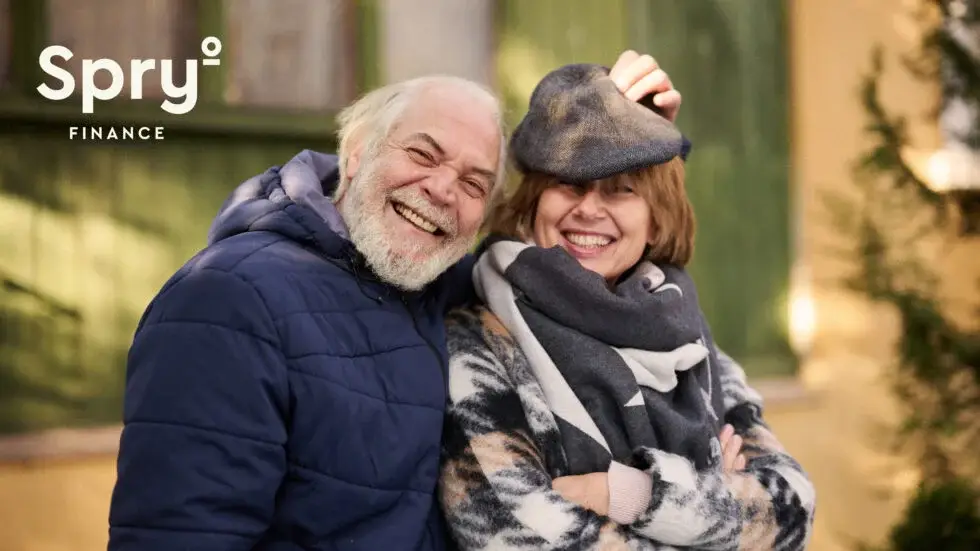 elderly couple smiling in winter coats outside